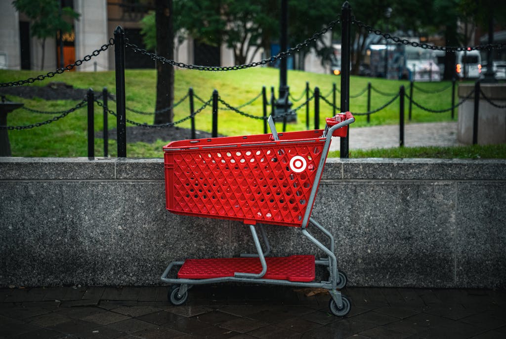 A red shopping cart is placed on a city street against a stone wall in Washington, DC.